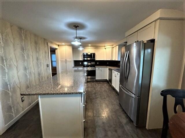 kitchen featuring pendant lighting, dark wood finished floors, stainless steel appliances, white cabinets, and dark stone countertops