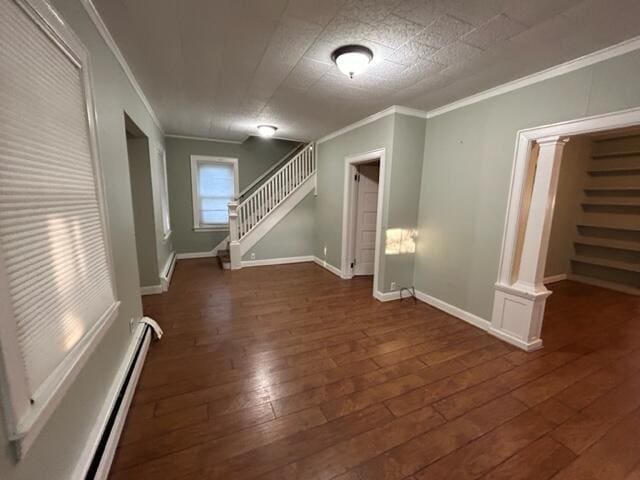 empty room featuring ornamental molding, dark wood-style flooring, stairway, and baseboards