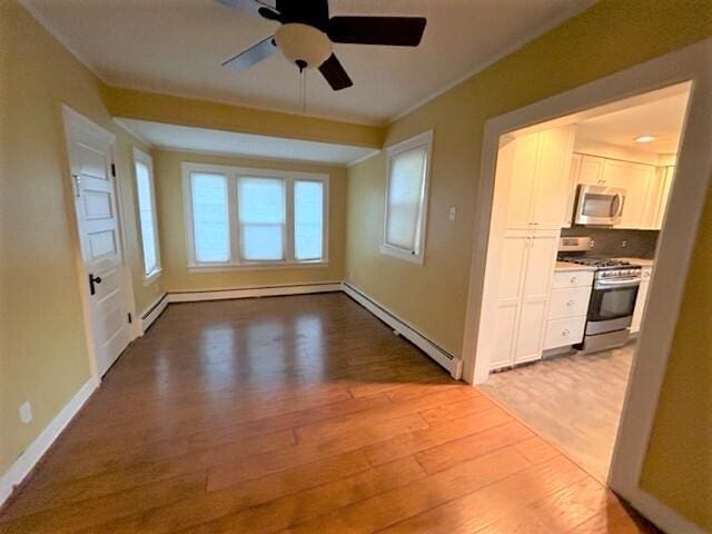 unfurnished room with light wood finished floors, baseboards, a ceiling fan, ornamental molding, and baseboard heating