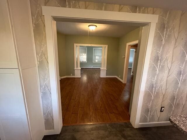 corridor with dark wood-style floors, baseboard heating, and baseboards