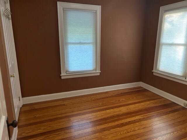 spare room with baseboards and wood finished floors