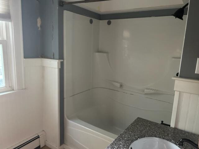 full bath with baseboard heating, plenty of natural light, a sink, and shower / tub combination