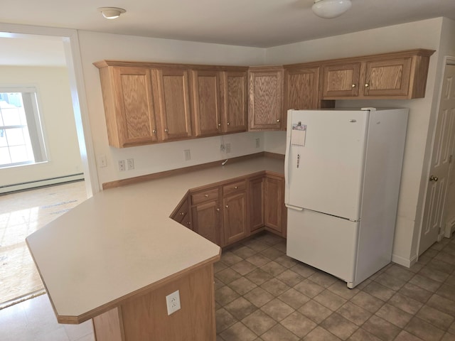 kitchen with freestanding refrigerator, light countertops, a peninsula, and baseboard heating