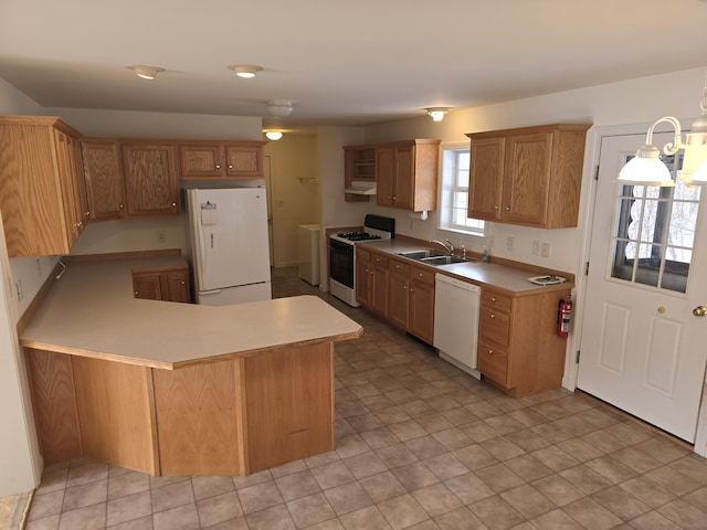 kitchen with white appliances, washer / dryer, a peninsula, light countertops, and a sink