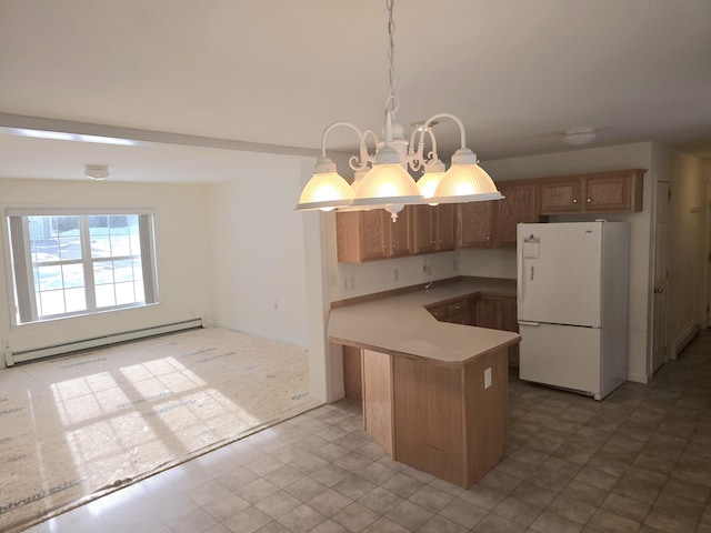 kitchen featuring a baseboard radiator, light countertops, freestanding refrigerator, brown cabinetry, and decorative light fixtures