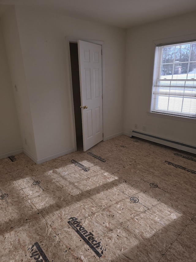 empty room featuring a baseboard heating unit and baseboards