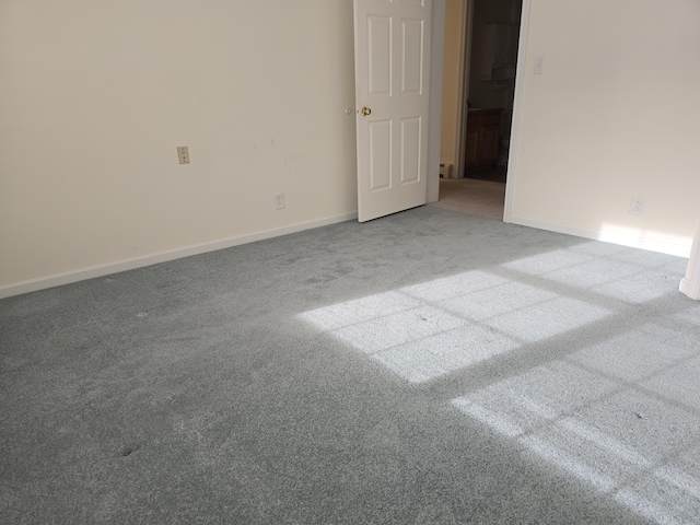 spare room featuring carpet floors and baseboards