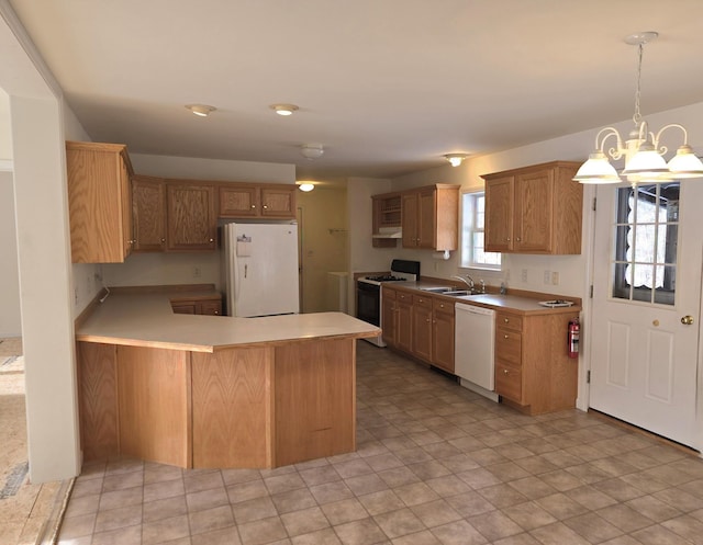 kitchen with decorative light fixtures, light countertops, a sink, white appliances, and a peninsula