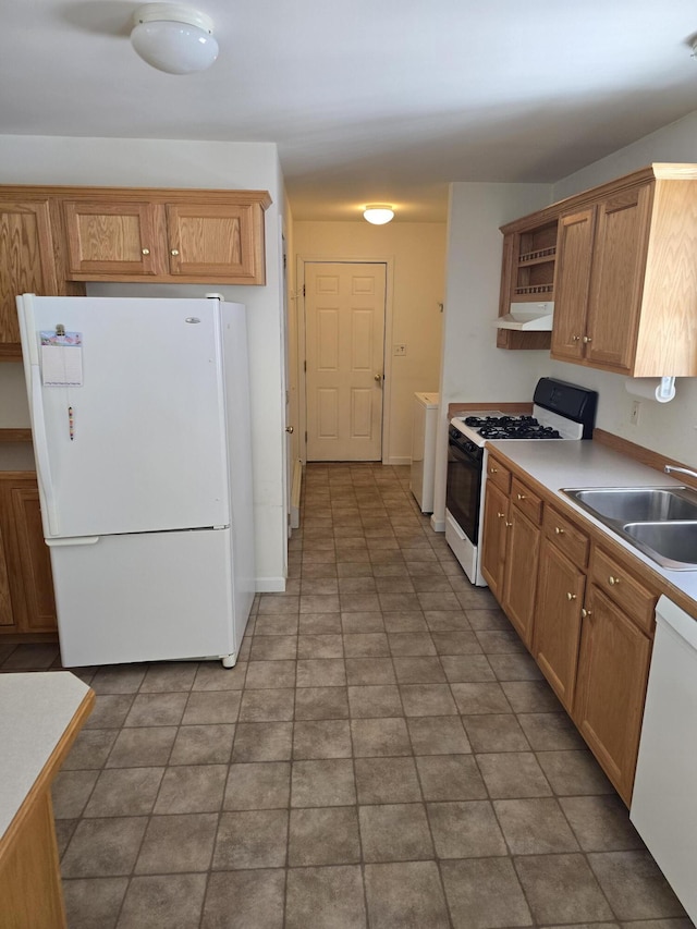 kitchen with washing machine and dryer, under cabinet range hood, white appliances, a sink, and light countertops