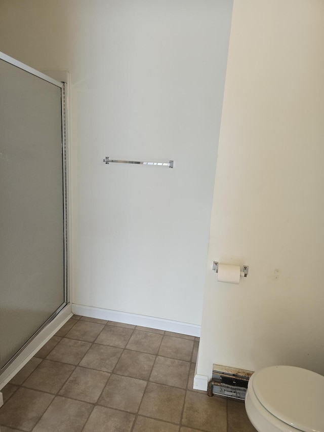 bathroom with a stall shower, baseboards, toilet, and tile patterned floors