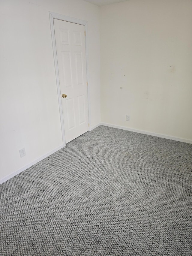 carpeted spare room featuring baseboards