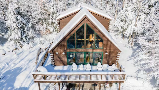 snow covered rear of property with log exterior