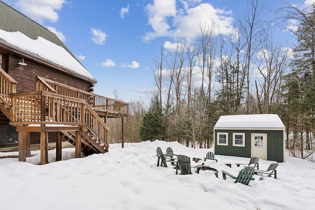 yard covered in snow with an outbuilding, stairway, and a wooden deck