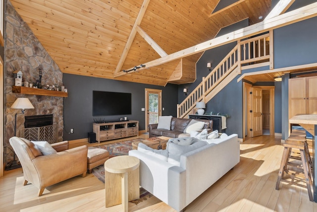 living room featuring high vaulted ceiling, a stone fireplace, wooden ceiling, wood finished floors, and stairs