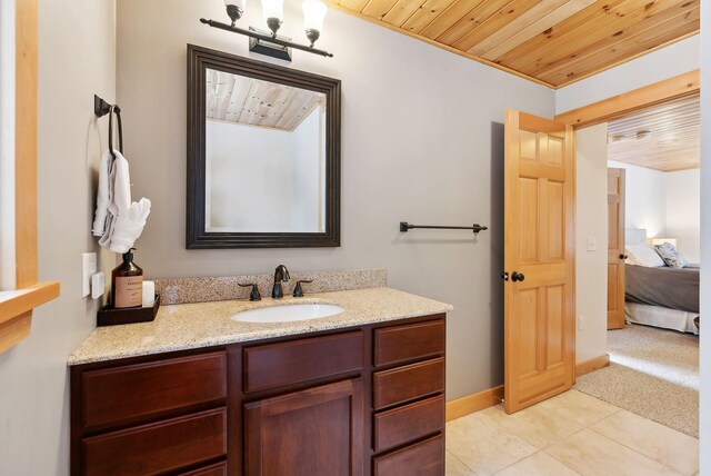 ensuite bathroom with tile patterned flooring, wooden ceiling, vanity, and baseboards