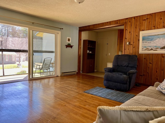 living room with plenty of natural light, a baseboard radiator, light wood finished floors, and a textured ceiling