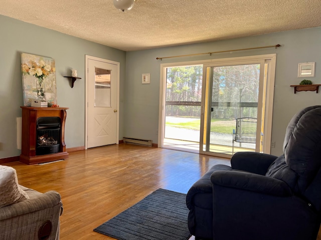 living room featuring a baseboard heating unit, light wood-style floors, a textured ceiling, and baseboards