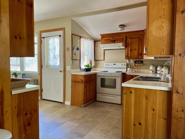 kitchen with brown cabinets, under cabinet range hood, light countertops, and electric range