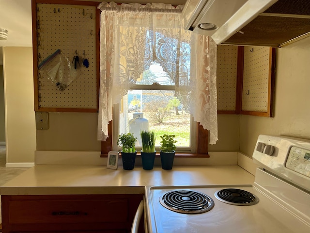 kitchen with light countertops, white range with electric cooktop, and under cabinet range hood