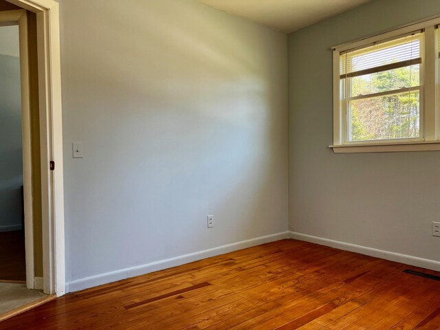 spare room with light wood-style floors, visible vents, and baseboards