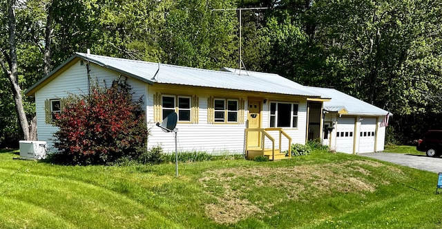 single story home with an attached garage, metal roof, a front lawn, and aphalt driveway