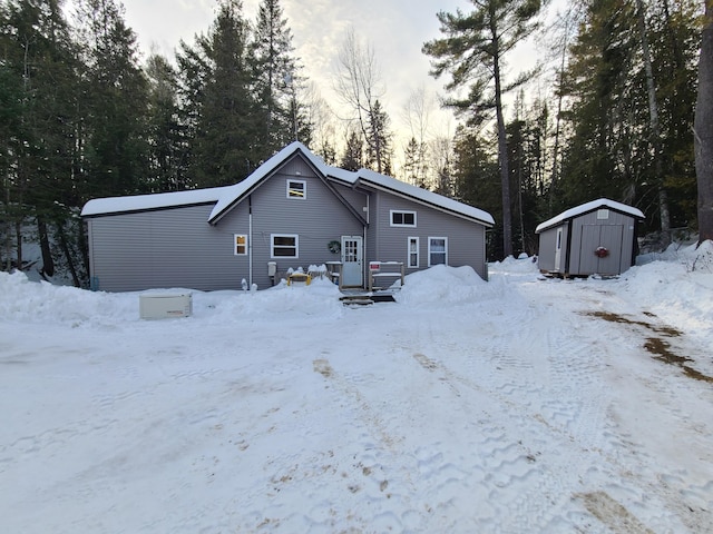 snow covered property featuring an outdoor structure and a storage unit