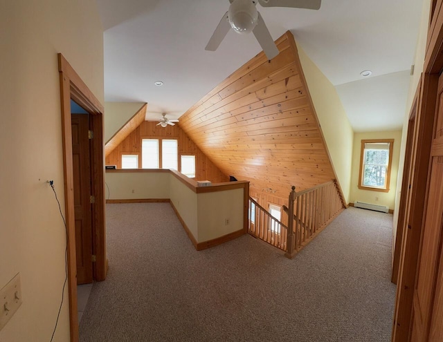 additional living space featuring lofted ceiling, light colored carpet, wood walls, baseboards, and baseboard heating