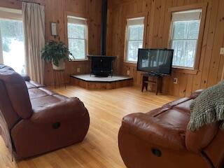 living room featuring a wood stove, wood walls, and light wood-style floors