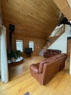 living room with a wood stove, wood ceiling, stairs, and wood finished floors