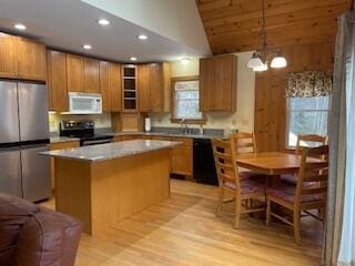 kitchen featuring a center island, pendant lighting, stainless steel appliances, light countertops, and glass insert cabinets