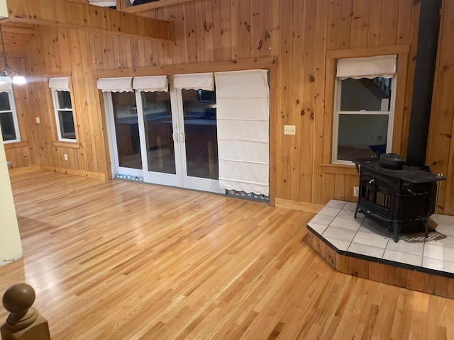 unfurnished living room featuring a wood stove, wood walls, and wood finished floors