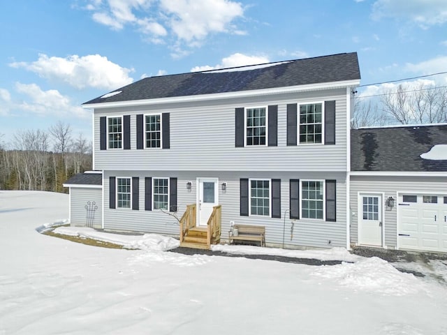 colonial house with an attached garage and a shingled roof