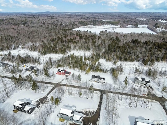 snowy aerial view featuring a forest view