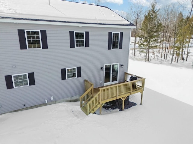 snow covered back of property featuring stairway and a wooden deck