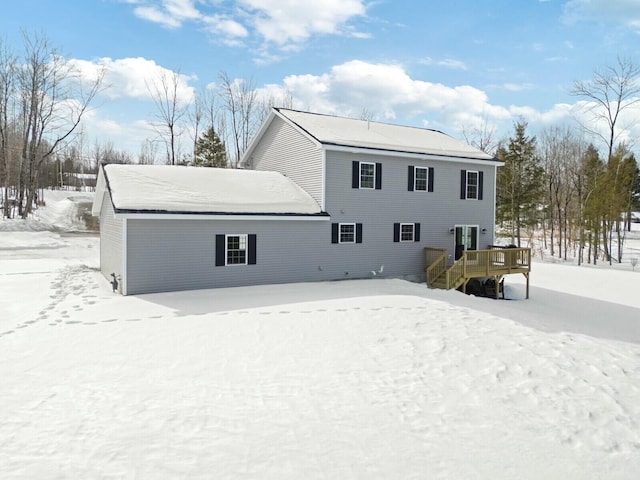 snow covered back of property with a deck