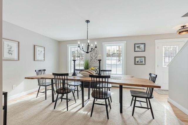 dining room featuring light wood-style floors, baseboards, and an inviting chandelier