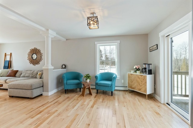 living area with a baseboard radiator, baseboards, decorative columns, and light wood finished floors