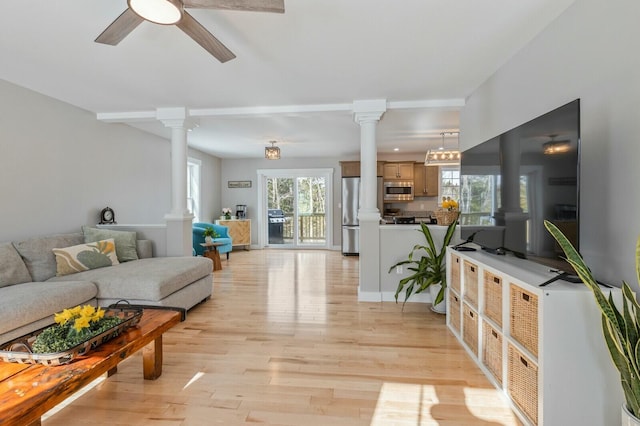 living room featuring ornate columns, ceiling fan, and light wood-style floors