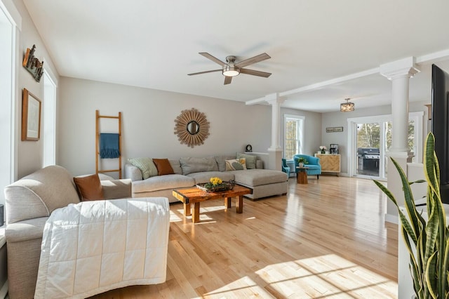 living area featuring a ceiling fan, light wood-style flooring, and ornate columns