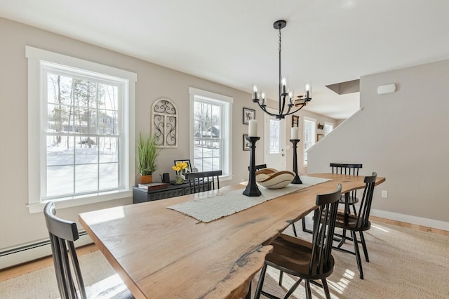 dining room featuring baseboards, light wood finished floors, and a notable chandelier