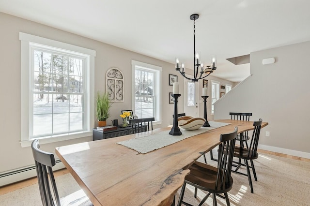 dining room featuring light wood-style flooring, baseboards, and an inviting chandelier