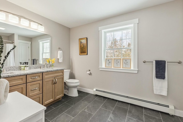 full bathroom with double vanity, baseboards, toilet, a baseboard heating unit, and a sink