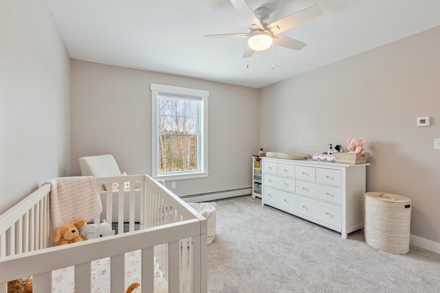 bedroom featuring light colored carpet, baseboard heating, ceiling fan, a crib, and baseboards