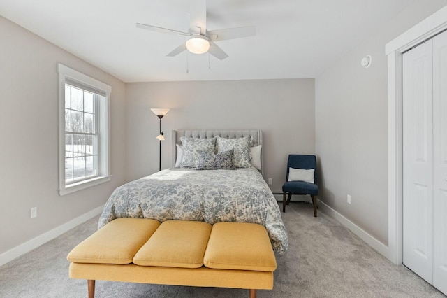 bedroom featuring a baseboard heating unit, light carpet, ceiling fan, and baseboards