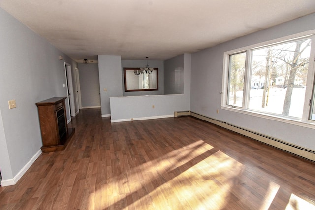 unfurnished living room with an inviting chandelier, a baseboard radiator, baseboards, and dark wood-style flooring