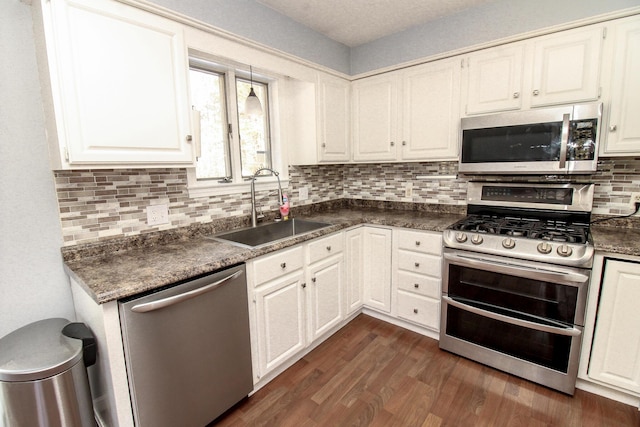 kitchen with appliances with stainless steel finishes, dark countertops, and white cabinetry