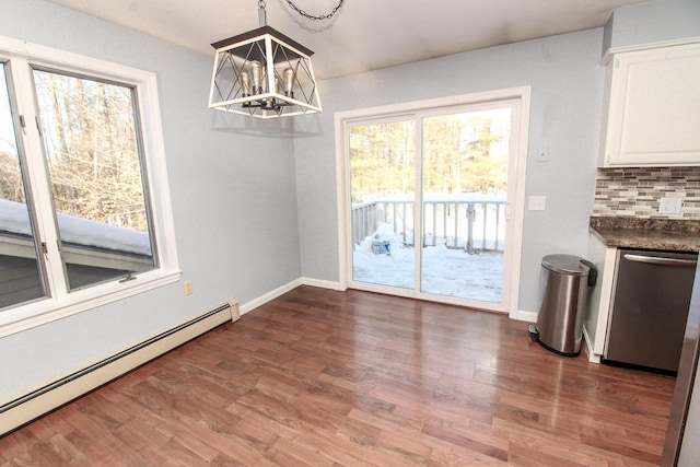 unfurnished dining area with baseboards, dark wood-style flooring, baseboard heating, and an inviting chandelier