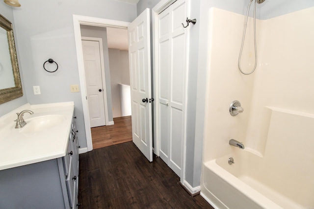 full bathroom with  shower combination, baseboards, wood finished floors, and vanity