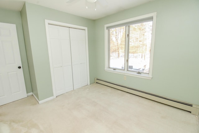 unfurnished bedroom with a baseboard heating unit, a closet, light carpet, and baseboards