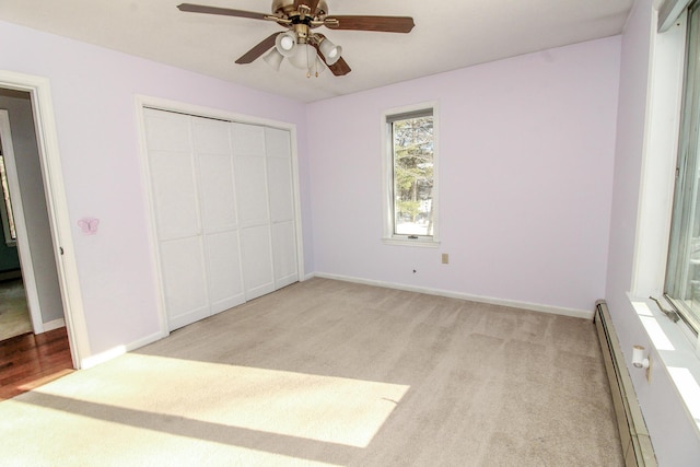 unfurnished bedroom with light colored carpet, a closet, baseboards, and baseboard heating